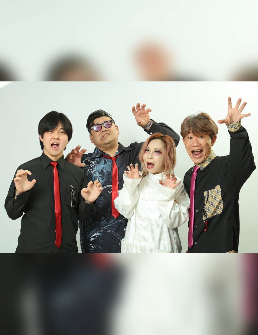 紫のライブ照明の下で並ぶQEUSICの4人